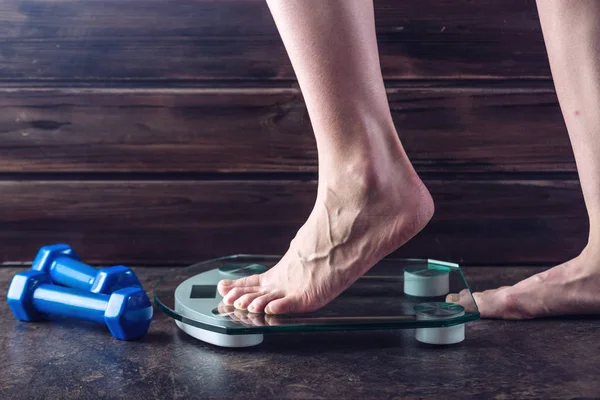 Kobiece nogi stojąc na wagi elektroniczne, do kontroli masy ciała na ciemnym tle. Koncepcja treningu, diety sportowego — Zdjęcie stockowe