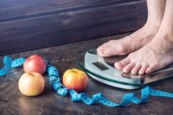 Piedini femminili in piedi su bilance elettroniche per il controllo del peso su fondo scuro. Concetto di allenamento sportivo, diete — Foto Stock