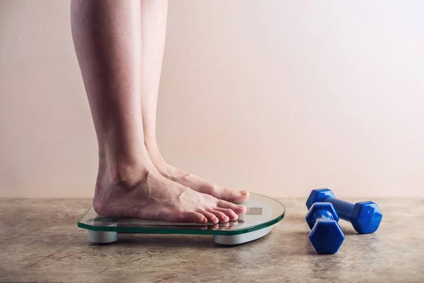 Ženské nohy stojící na elektronické váhy pro regulaci hmotnosti na světlé pozadí. Koncepce sportovního tréninku, strava — Stock fotografie