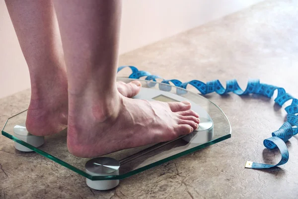 Piedini femminili in piedi su bilance elettroniche per il controllo del peso su fondo chiaro. Concetto di allenamento sportivo, diete — Foto Stock