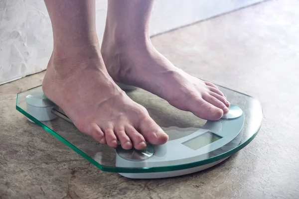 Piedini femminili in piedi su bilance elettroniche per il controllo del peso su fondo chiaro. Concetto di allenamento sportivo, diete — Foto Stock