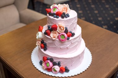 Güzel zarif üç katmanlı pembe düğün pastası meyveler ve çiçekler ile dekore edilmiştir. Şeker sakız da kavramı Pastane