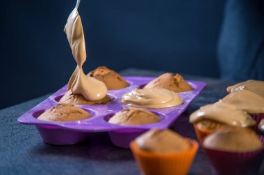 Şef pasta krem koyu arka plan üzerinde taze hazırlanmış kek üzerinde yağıyor. Şekerleme yemek kavramı