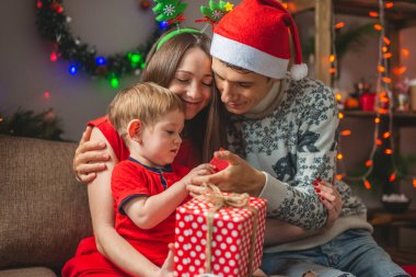 Anne ve baba oğullarına kırmızı kutuda bir hediye verir. Çocuklu genç aile Noel 'i ve yeni yılı evde kutluyor.