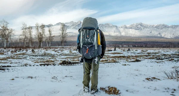 Hombre excursionista con una mochila de pie con la espalda mirando a las montañas nevadas por delante. Camino hacia el logro de la meta —  Fotos de Stock