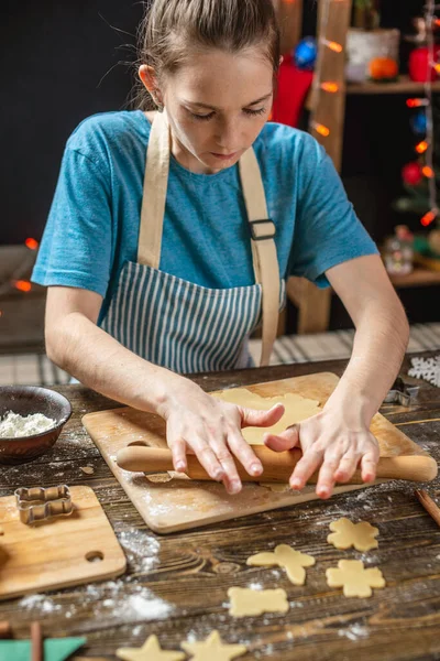 젊은 여자는 축제용 생강 쿠키를 요리하기 위해 반죽을 만든다. 크리스마스 이브의 아늑 한 가정 분위기 — 스톡 사진