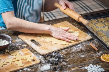 Kadın hamuru oklavayla yuvarlıyor ve zencefilli ekmeği şekillendiriyor. Lezzetli kurabiyeler pişirmek için Noel havası.