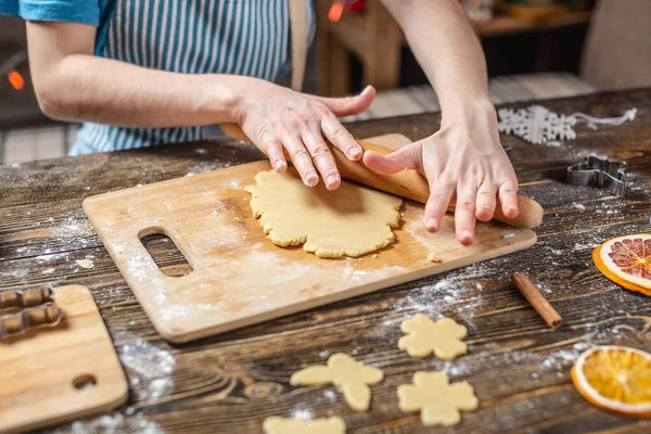 Женщина выкатывает тесто со скалкой и формирует праздничные пряники. Рождественское время приготовления вкусного печенья . — стоковое фото