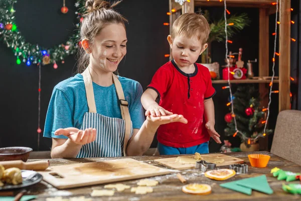 Mother and child son shape the dough for baking homemade holiday gingerbread. Family cooking in Christmas decorations — Stock Photo, Image