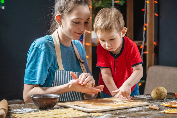 Mother and child son shape the dough for baking homemade holiday gingerbread. Family cooking in Christmas decorations — Stock Photo, Image