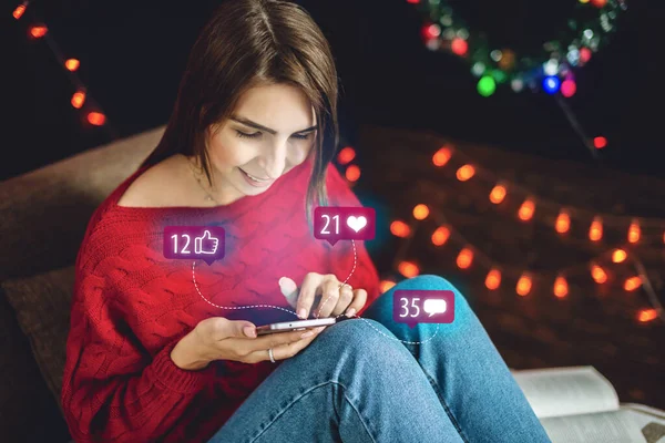Wanita yang menggunakan ponselnya menghabiskan waktu untuk melihat-lihat ke layar sosial dan membaca komentar-komentar pada hari Natal — Stok Foto