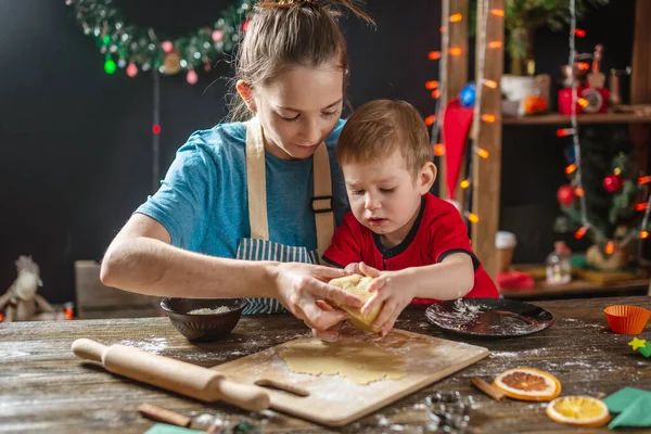 Mom and child son shape the dough for baking homemade holiday cookies. Family cooking in Christmas decorations — Stock Photo, Image