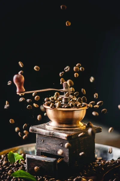 Coffee beans falling on wooden vintage coffee grinder. Grinding fragrant freshly roasted coffee — Stock Photo, Image