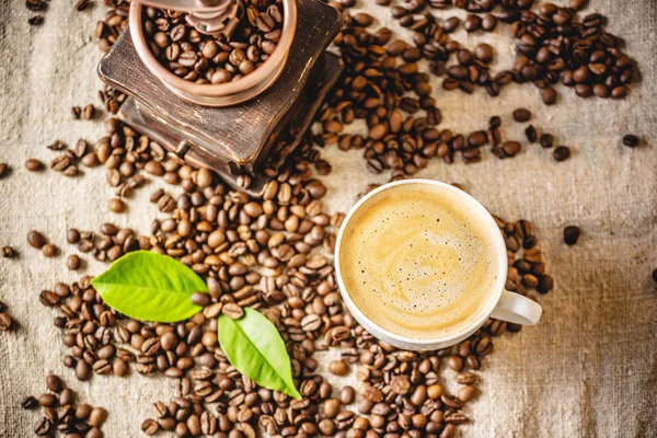 Copo de café com espuma e um moedor de café vintage de madeira. Bebida revigorante perfumada de feijão assado recentemente. — Fotografia de Stock