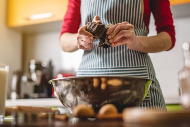 Aşçı ev hanımı renkli bir mutfakta kurabiye yapıyor. Hamuru hazırlamak için rende çikolataya sürtünen kadın.