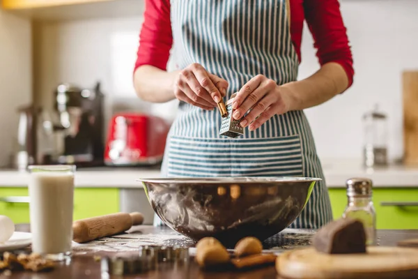 Cocinar ama de casa haciendo galletas en casa en una cocina colorida. Mujer frotando en canela rallador para preparar la masa — Foto de Stock