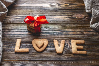 Sevgi şeklinde tatlı bir kurabiyeden ve kırmızı kurdeleyle bağlanmış bir hediye. Romantik Sevgililer Günü hediyesi