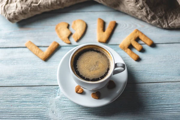 Copo de café e uma mensagem de um biscoito doce na forma da palavra amor. Presente romântico do dia dos namorados — Fotografia de Stock