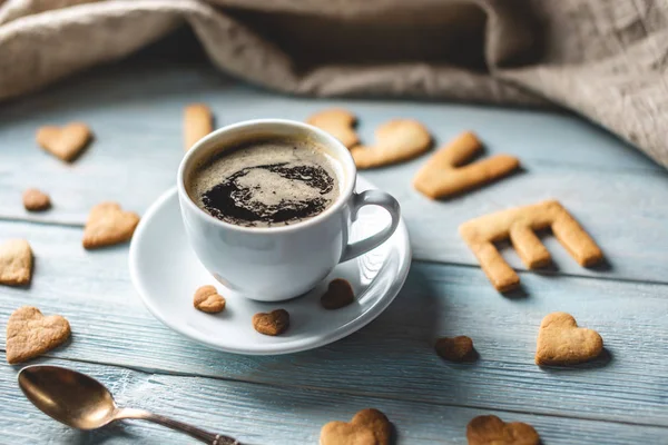 Copo de café e uma mensagem de um biscoito doce na forma da palavra amor. Presente romântico do dia dos namorados — Fotografia de Stock