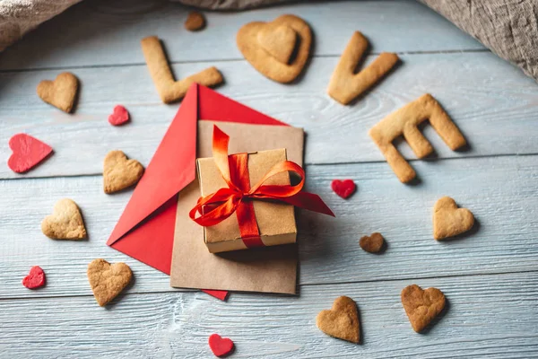 Mensagem de um biscoito doce na forma da palavra amor e um presente amarrado com fita vermelha. Presente romântico do dia dos namorados — Fotografia de Stock