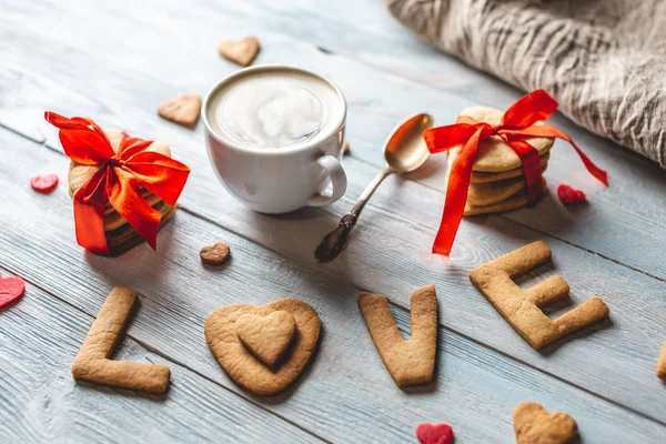 Copo de café e uma mensagem de um biscoito doce na forma da palavra amor. Presente romântico do dia dos namorados — Fotografia de Stock