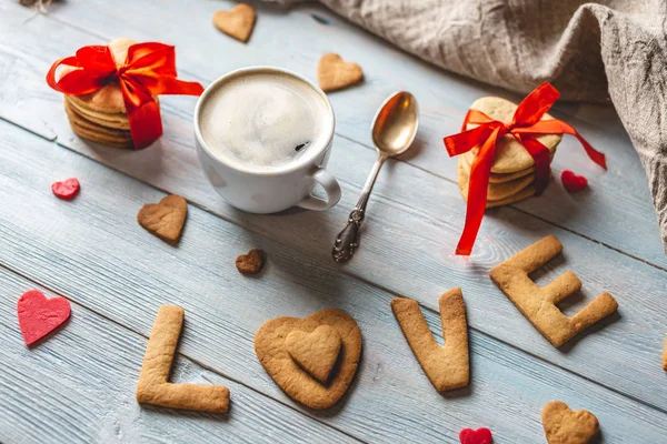 Copo de café e uma mensagem de um biscoito doce na forma da palavra amor. Presente romântico do dia dos namorados — Fotografia de Stock