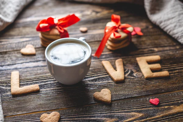 Copo de café e uma mensagem de um biscoito doce na forma da palavra amor. Presente romântico do dia dos namorados — Fotografia de Stock