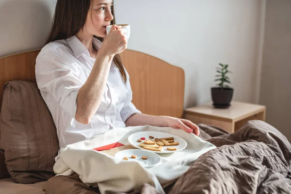 Woman have a romantic Breakfast in cozy morning bed. Café y palabra amor de las galletas. Sorpresa en el día de San Valentín — Foto de Stock