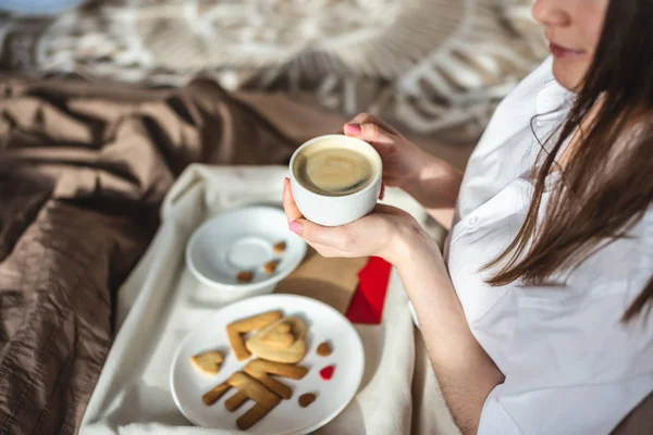 Giovane donna hanno una colazione romantica nel letto del mattino. Caffè e parola amore dai cookie. Sorpresa il giorno di San Valentino — Foto Stock