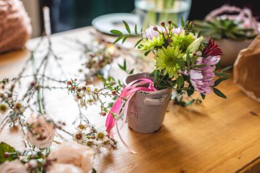 Çiçekçi masaüstünde bir çiçek kompozisyonu topluyor. Çiçekçide rengarenk bahar buketi