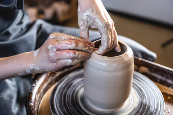 Potter egy fazekas keréken dolgozik, vázát készít. Nő alkotó agyag a kezét alkotó kancsó egy műhelyben — Stock Fotó