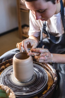 Potter, Potter 'ın çarkında vazo yapıyor. Kadın elleriyle kil oluşturuyor, atölyede sürahi yapıyor..