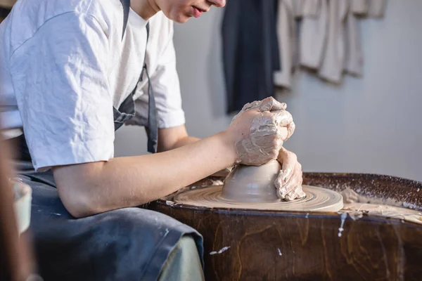 Potter trabajando en una rueda de Potter haciendo un jarrón. Mujer joven formando la arcilla con las manos creando jarra en un taller . — Foto de Stock