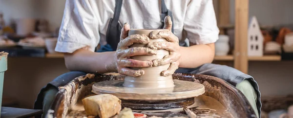 Potter trabajando en una rueda de Potter haciendo un jarrón. Mujer joven formando la arcilla con las manos creando jarra en un taller . — Foto de Stock