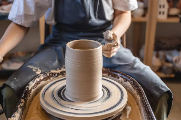 Mujer alfarera trabajando en la rueda de Potter haciendo un jarrón. Maestro formando la arcilla con sus manos creando jarra en un taller — Foto de Stock