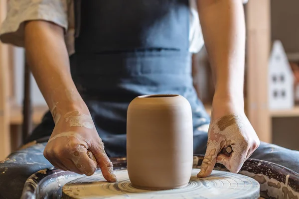 Una alfarera trabajando en una rueda de Potter haciendo un jarrón. Maestro saca la jarra del círculo suavemente sosteniéndola en las manos — Foto de Stock