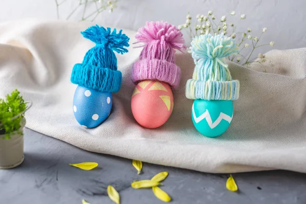 Яркие красочные пасхальные яйца в вязаных зимних шляпах на сером фоне. Праздничная весенняя пасхальная карта — стоковое фото