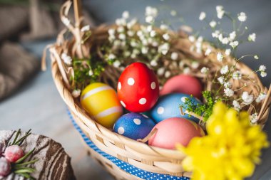 Ahşap bir masanın üzerinde renkli parlak yumurtalar olan bayramlık Paskalya sepeti. Geleneksel bahar tatili