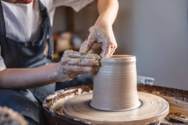 Potter, Potter 'ın çarkında vazo yapıyor. Kadın, bir atölyede sürahi yaratarak kilin şeklini alıyor. Kapat.