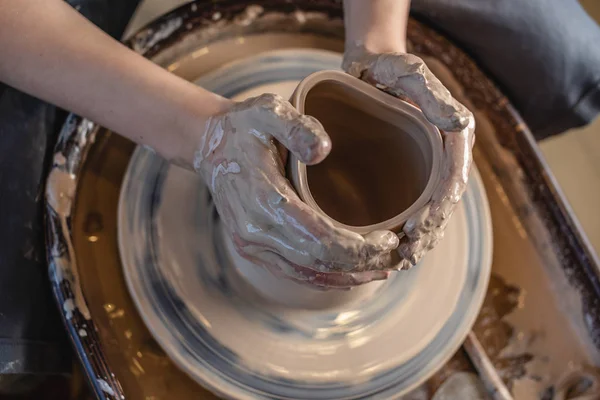 Potter arbeitet an einem Töpferrad, das eine Vase herstellt. Frau formt Ton mit Händen, die Krug in einer Werkstatt herstellen. Ansicht von oben — Stockfoto