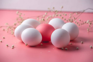 Bright pink Easter egg among white ones on a pastel background. Festive spring card