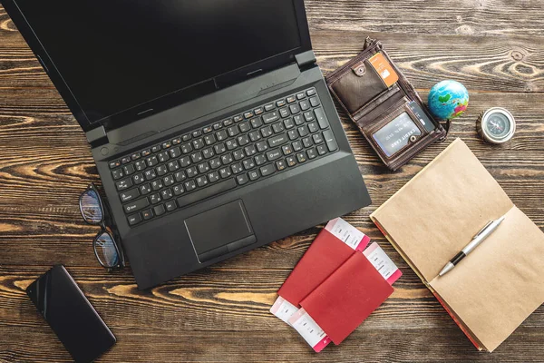 Preparing for an exciting journey. Booking flights and paying with a credit card using a laptop on a wooden background. The view from the top.