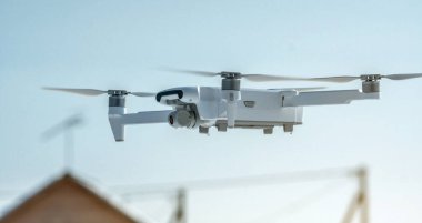 Kameralı bir kuadrokopter dron mavi gökyüzüne karşı havada asılı duruyor. Yükseklikten fotoğraf ve video çekiyoruz. İnsansız araçların modern teknolojileri