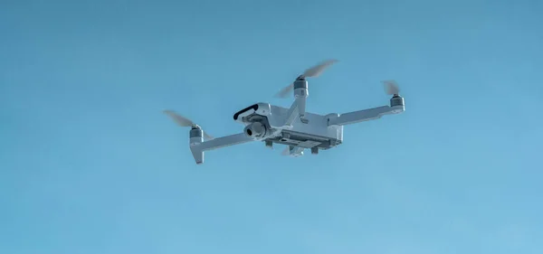 A quadrocopter drone with camera hangs in the air against a blue sky. Shooting photos and videos from the air at altitude. Modern technologies of unmanned vehicles