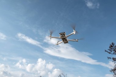 Kameralı beyaz kuadrokopter dron kışın güzel doğanın arka planında asılı duruyor. Yükseklikten fotoğraf ve video çekiyoruz. İnsansız araçların modern teknolojileri