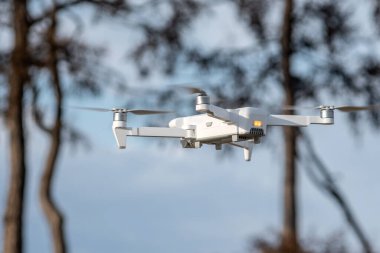 Kameralı beyaz kuadrokopter dron kışın güzel doğanın arka planında asılı duruyor. Yükseklikten fotoğraf ve video çekiyoruz. İnsansız araçların modern teknolojileri