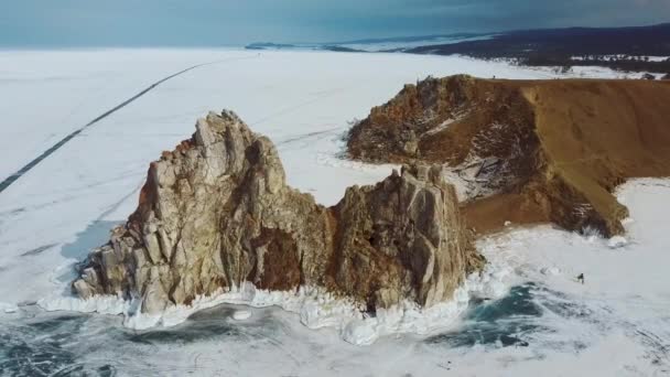 Rocha no gelo do inverno Baikal na ilha Olkhon, na Sibéria. Bela natureza: montanhas, lago congelado, céu . — Vídeo de Stock