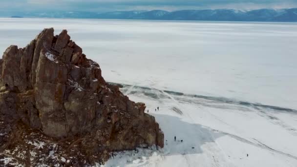 Rocha no gelo do inverno Baikal na ilha Olkhon, na Sibéria. Bela natureza: montanhas, lago congelado, céu . — Vídeo de Stock