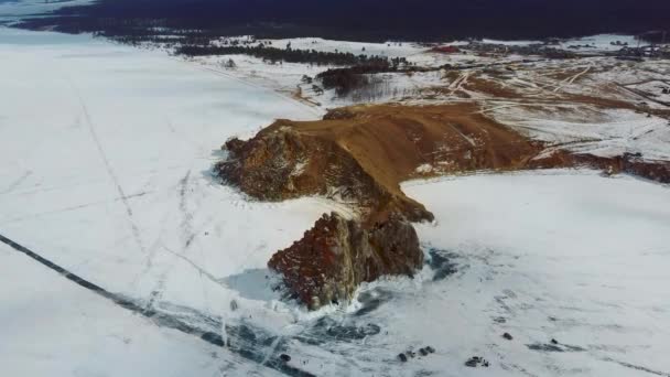시베리아의 올 크론 섬에 있는 바이칼호의 얼음 위에 바위가 있습니다. 아름다운 자연: 산, 얼어붙은 호수, 하늘. — 비디오