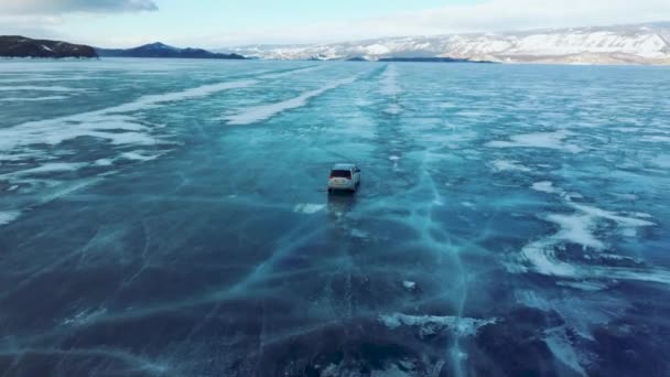 Autoritten op het blauwe ijs van het Baikalmeer in de winter. Tracking view vanaf de achterkant van de quadcopter — Stockvideo